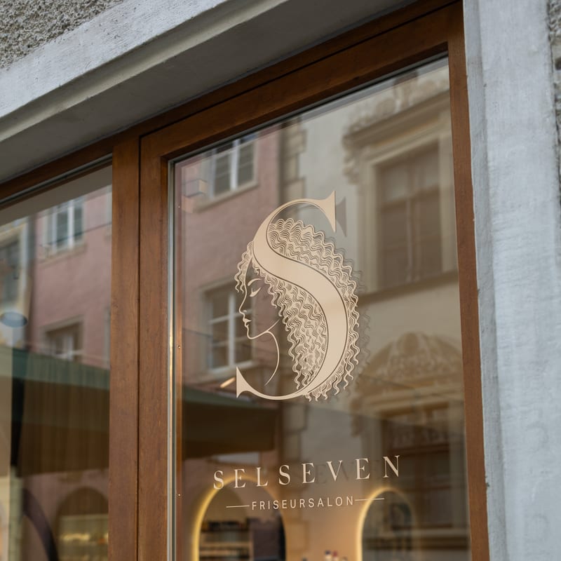 Die Glastür des Salons mit dem Selseven-Logo und dem Schriftzug „Selseven Friseursalon“
