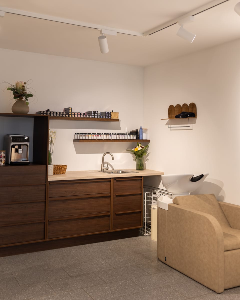 Der Waschplatz mit Sessel und Becken, darüber Regale mit Haarfarben
